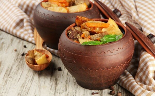 Warm stew in a pot beside a plate of grains, ready to serve